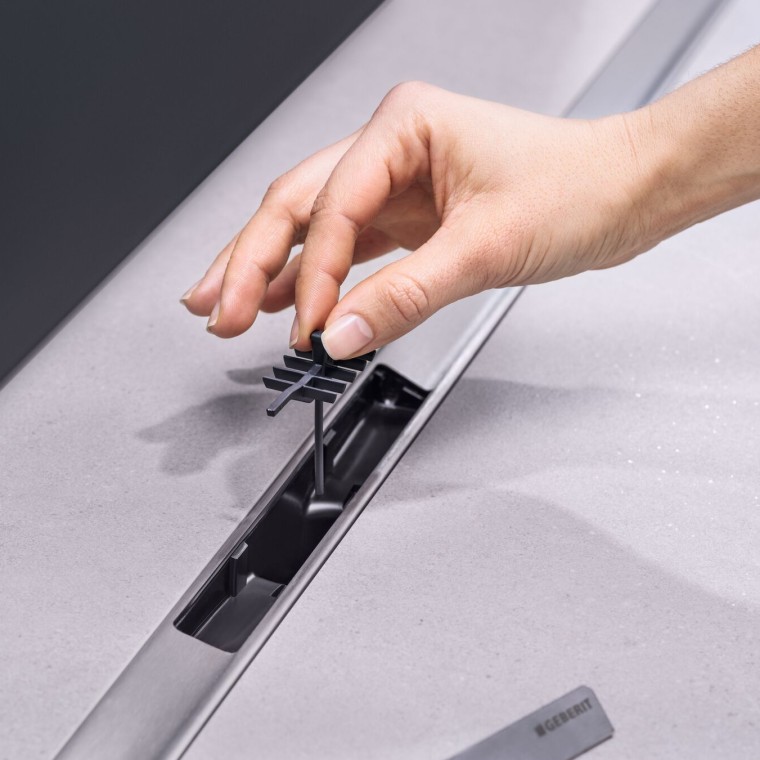 Roka, ki vstavlja nastavek z glavnikom v odtok Roka, ki vstavlja nastavek z glavnikom v odtok