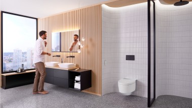 Moški v kopalnici stoji pred ogledalom Geberit Option Plus Square in črnim kopalniškim pohištvom Geberit ONE (© Geberit)
