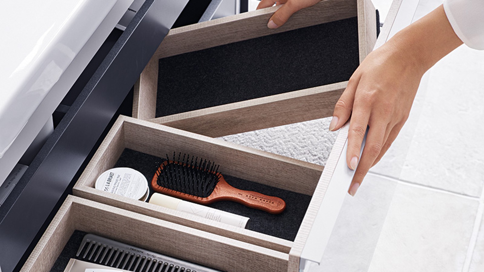 Roka odpre enega od predalov omarice za umivalnik Geberit Acanto v dizajnu naravnega lesa