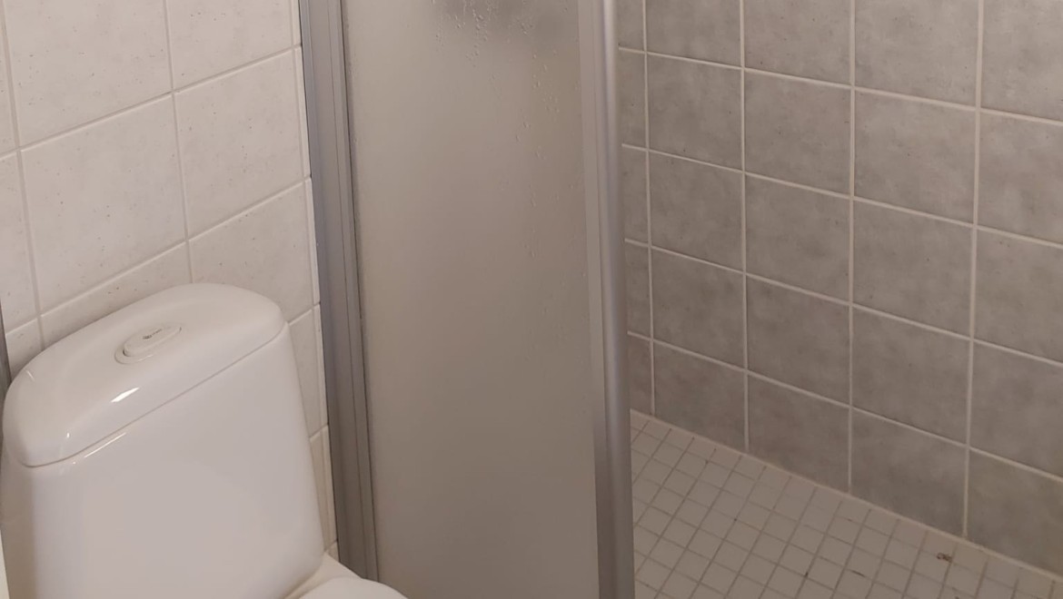 Slika pred prenovo s pogledom na kabino za prhanje in stoječo WC školjko (© Meja Hynynen) Slika pred prenovo s pogledom na kabino za prhanje in stoječo WC školjko (© Meja Hynynen)
