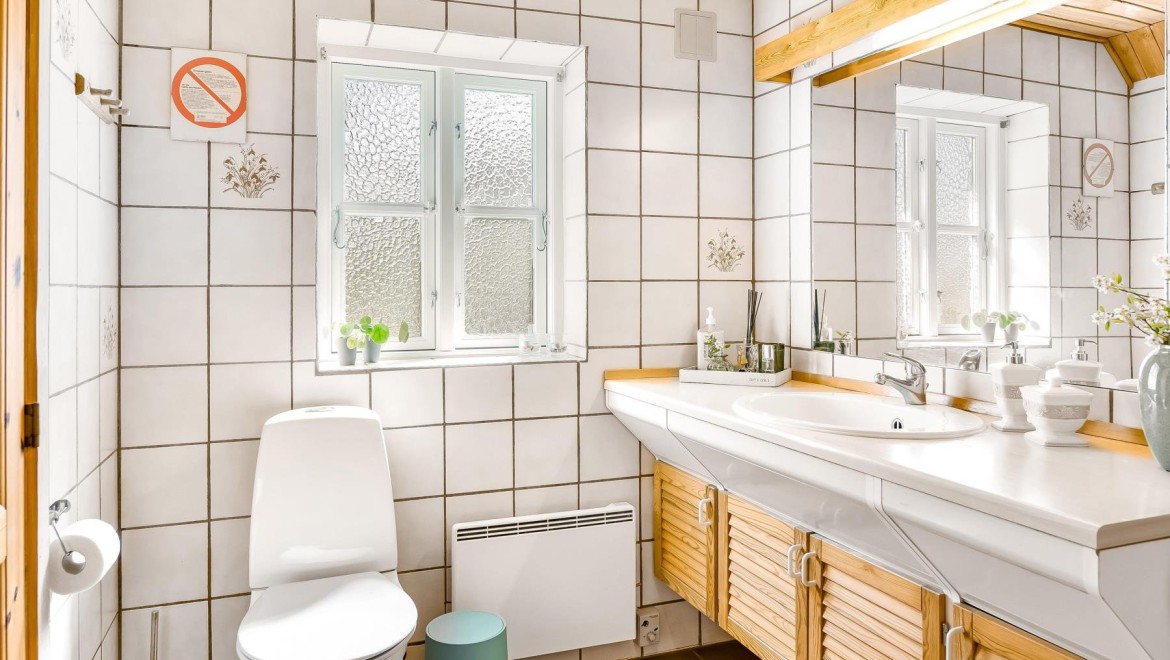 Originalna kopalnica s talno WC školjko, belimi ploščicami in lesenim kopalniškim pohištvom (© @triner2 in @strandparken3)