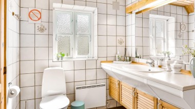 Originalna kopalnica s stoječo WC školjko, belimi ploščicami in lesenim kopalniškim pohištvom (© @triner2 in @strandparken3)