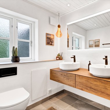 Svetla, prenovljena kopalnica z dvema okroglima umivalnikoma, velikim ogledalom in lesenim kopalniškim pohištvom (© @triner2 in @strandparken3)