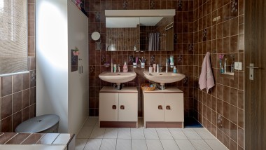 Kopalnica z rjavimi ploščicami in dvema umivalnikoma