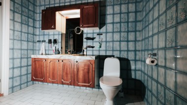 Kopalnica z modrimi ploščicami in stoječo WC školjko