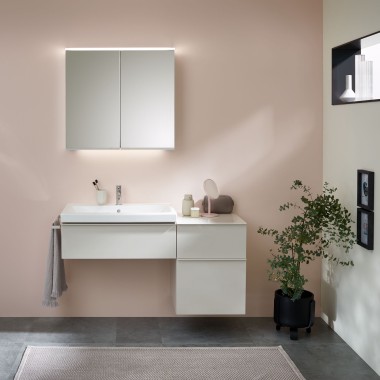 Umivalnik s kopalniškim pohištvom, umivalnikom in omarico z ogledalom Geberit pred pastelno steno
